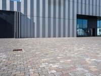 a brick walkway outside of a business building, with a large windowed front door