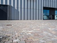 a brick walkway outside of a business building, with a large windowed front door