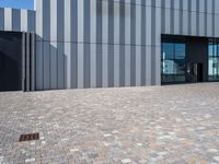 a brick walkway outside of a business building, with a large windowed front door