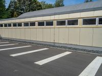 a metal building with a corrugated door in front of it and trees lining the street behind it