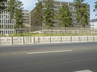 a traffic light sitting on the side of a road near a building and trees with tall trees