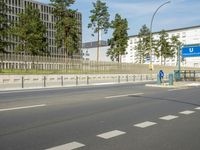 a traffic light sitting on the side of a road near a building and trees with tall trees