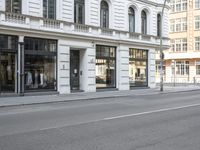 a person on a bicycle rides down the street next to buildings and some stores are empty