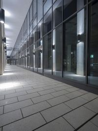 a street with stone floors and tall windows in it and lots of columns underneath the walkway