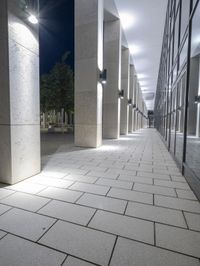 a street with stone floors and tall windows in it and lots of columns underneath the walkway