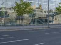 a glass building reflecting the building's architecture near a road side stop signal with trees