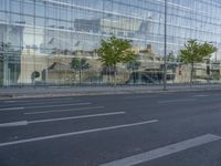 a glass building reflecting the building's architecture near a road side stop signal with trees