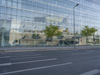 a glass building reflecting the building's architecture near a road side stop signal with trees