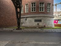 a small intersection next to a brick building and a road that is covered in cobbles