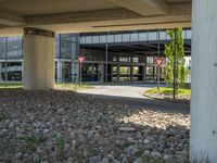 a concrete building with three red triangle road signs on the side of it under an overpass