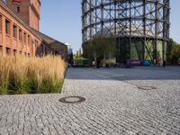 the large red brick building next to the tall tall tower is a manhole and there is gravel ground