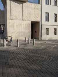 a person with a suitcase walking across an outside courtyard in front of a building,