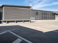 a large garage with grey metal fence surrounding the entrance and two white cars parked inside