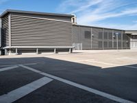 a large garage with grey metal fence surrounding the entrance and two white cars parked inside