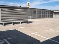 a large garage with grey metal fence surrounding the entrance and two white cars parked inside