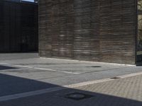 the man rides down the sidewalk on a skateboard in his red coat in front of a building