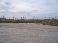 large piles of dirt on a parking lot in the daytime with power poles in background