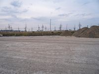 large piles of dirt on a parking lot in the daytime with power poles in background