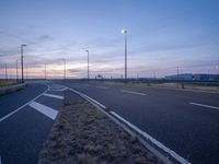 empty highway with two white stripes on one side and several lights on the other side