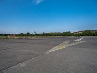 a paved parking lot with two airplanes and blue sky in the background, showing how far off