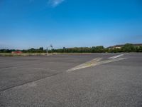 a paved parking lot with two airplanes and blue sky in the background, showing how far off