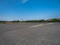 a paved parking lot with two airplanes and blue sky in the background, showing how far off