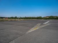 a paved parking lot with two airplanes and blue sky in the background, showing how far off