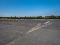 a paved parking lot with two airplanes and blue sky in the background, showing how far off