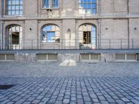 an empty brick courtyard with a fire hydrant in the middle of it and three windows to the right