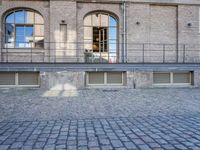 an empty brick courtyard with a fire hydrant in the middle of it and three windows to the right