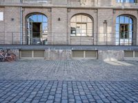 an empty brick courtyard with a fire hydrant in the middle of it and three windows to the right