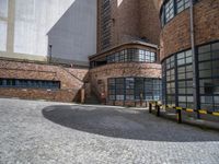 a large building with glass windows is located in the center of a circular brick area