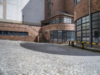 a large building with glass windows is located in the center of a circular brick area