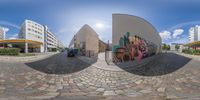 a photograph taken from a fisheye lens with a street below, with buildings, and a bus,