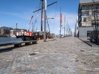 a dock with boats docked at the docks and a bench nearby to them that is in a brick area