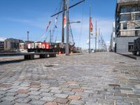 a dock with boats docked at the docks and a bench nearby to them that is in a brick area