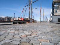 a dock with boats docked at the docks and a bench nearby to them that is in a brick area