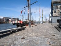 a dock with boats docked at the docks and a bench nearby to them that is in a brick area