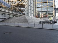 bicycles sit outside on the steps of a building next to a street lined with parking meters