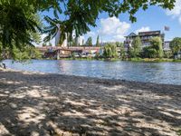 the view from a bench at the river bank near the park benches and buildings in the distance