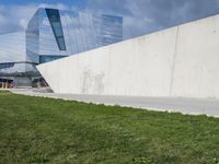 the modern building has large windows on top of it's walls, in front of a grass yard