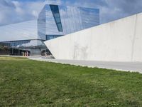 the modern building has large windows on top of it's walls, in front of a grass yard