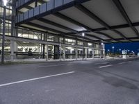 a empty street with an overpass and a streetlight at night time - -