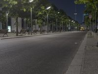 empty street with benches and lamp poles near sidewalk in city at night time on sunny day