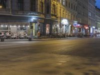 an empty city street at night with lights streaking through the buildings and a person on the sidewalk next to the stoplight