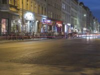 an empty city street at night with lights streaking through the buildings and a person on the sidewalk next to the stoplight