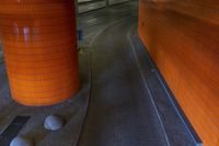 two orange cement pillars in a corner with concrete balls at the top of them and two silver granite ones behind them