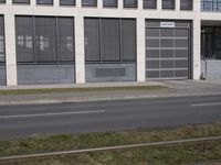 this is an empty sidewalk in front of a building with closed doors and blinds on it