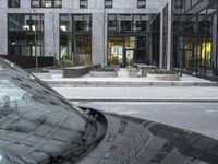 an empty car sitting on the road in front of a building next to another car