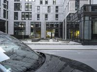 an empty car sitting on the road in front of a building next to another car